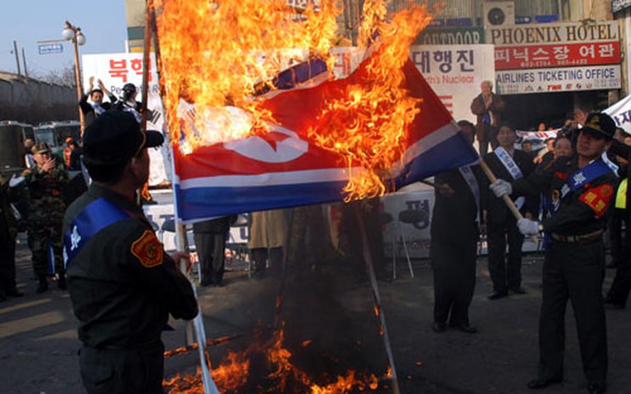 Two former South Korean marines light a North Korean flag on fire at a rally outside Osan Air Base, South Korea, Wednesday.