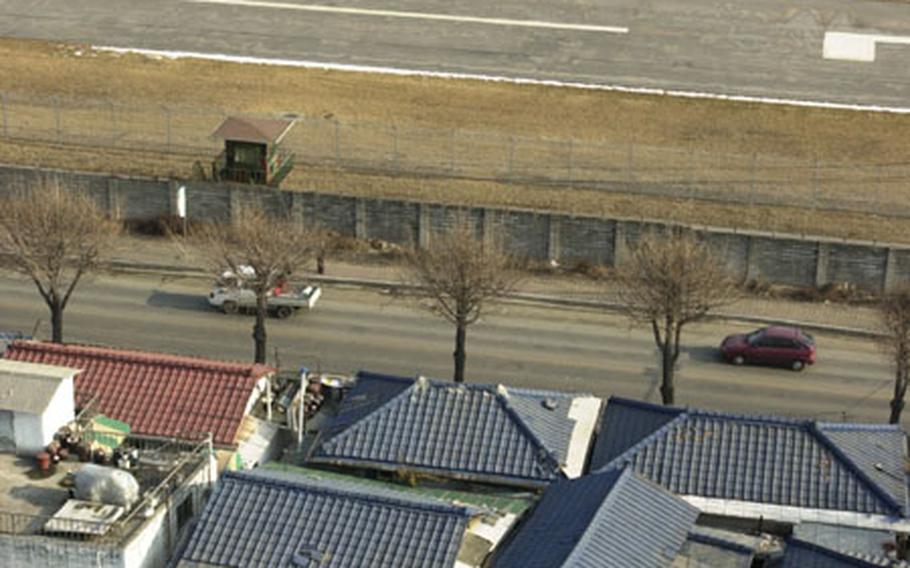 An AH-64D Apache Longbow runs inside the confines of Camp Casey, South Korea, which is surrounded by the city of Chuncheon. Homes and apartment buildings have been built around the small camp over the years.
