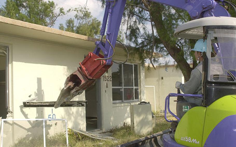 A heavy equipment operator uses a mechanical claw to rip off parts from a single-family home at Sada Family Housing Area. Demolition crews have begun knocking down hundreds of older homes in the housing area to make way for two high-rise towers totalling 136 units and 194 single- or two-story houses.