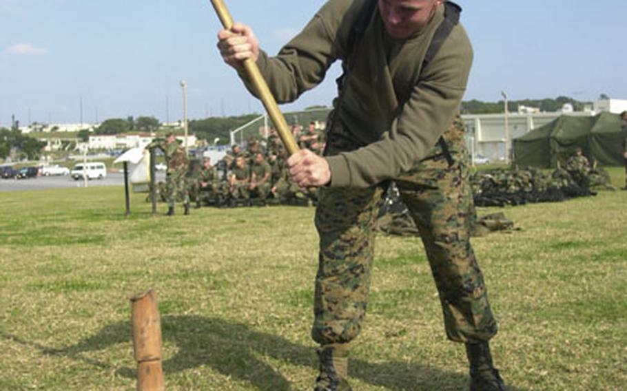 Marine Sgt. Brian Hatfield drives tent stakes into the ground with a sledgehammer during a "shakedown" period for a Marine support unit on Okinawa.