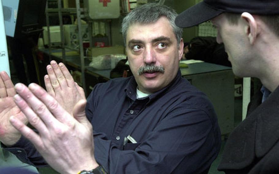 George Webb, a civilian technical representative of Northrop Grumman, talks about an electronics system for Naval aircraft with Petty Officer 3rd Class Timothy Russell aboard the USS Kitty Hawk.