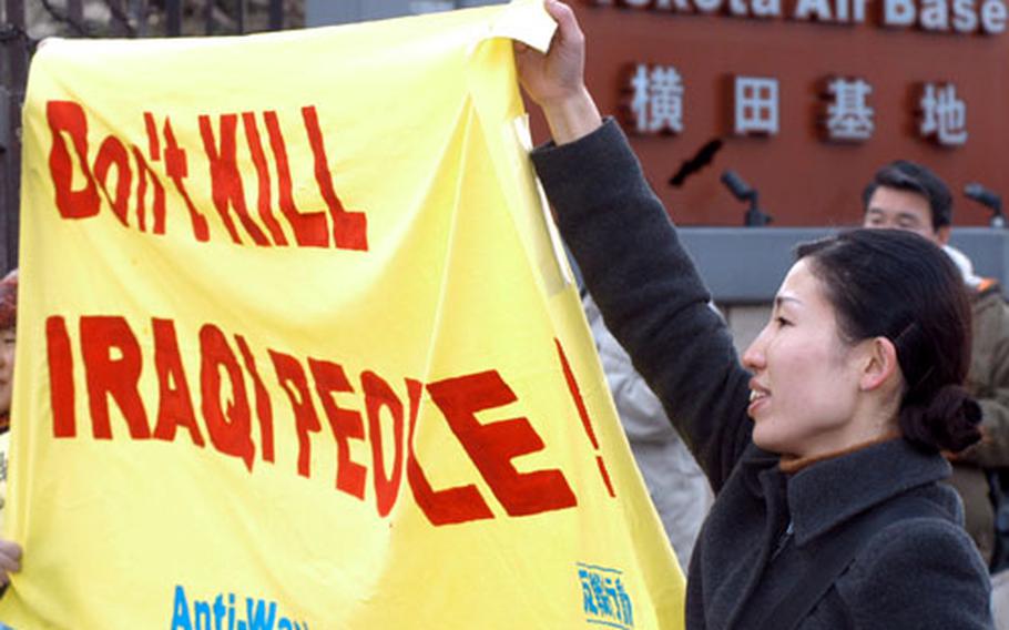 Midori Tachibana, 27, helps hold up a banner in front of the main gate at Yokota Air Base Saturday morning during an anti-war demonstration. The gate was closed to traffic — and Americans were scarce — for about 20 minutes, while about 80 Japanese protested a possible U.S.-led war against Iraq.