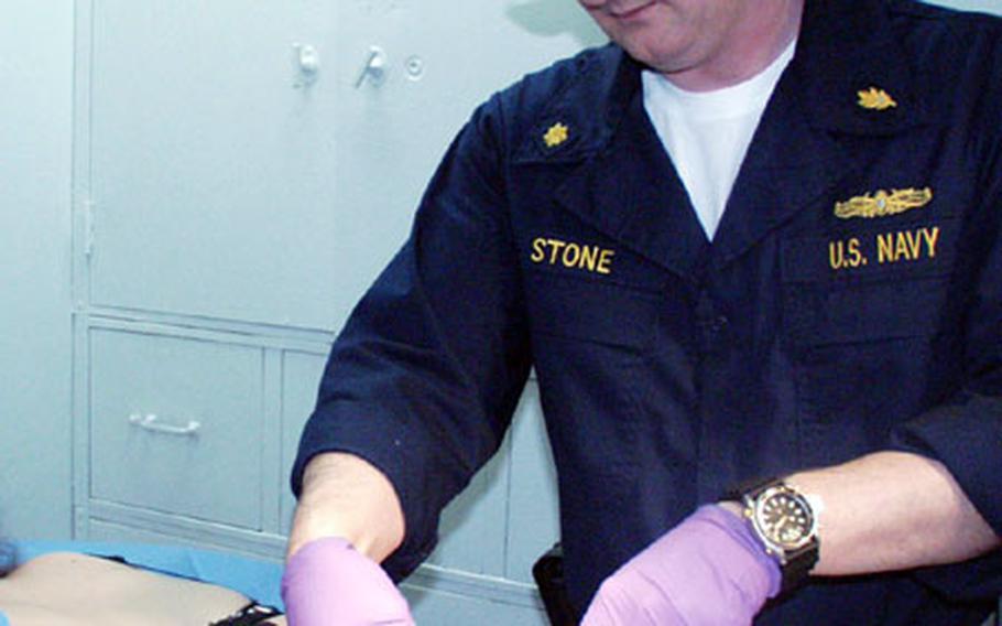 Lt. Cmdr. Jeff Stone, the senior medical officer on the USS La Salle, removes a fatty tumor from Seaman Jacki Harris' back on the ship in Gaeta, Italy. Stone said he got "slammed" — involuntarily assigned — when he was pulled out of a diving medical officer course and sent to North Carolina.