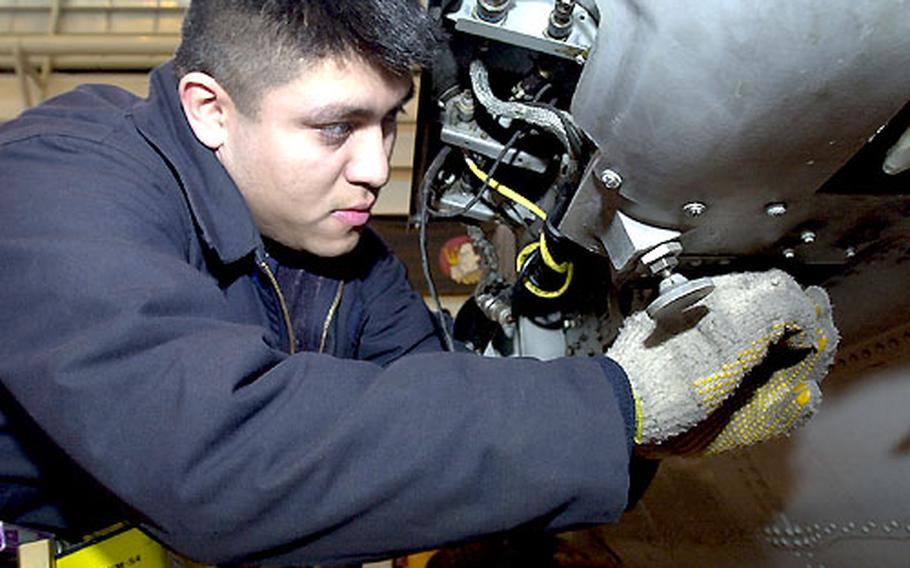 Petty Officer 2nd Class Ronnie Cubias adjusts an assembly that will hold a torpedo on a SH-60B helicopter.