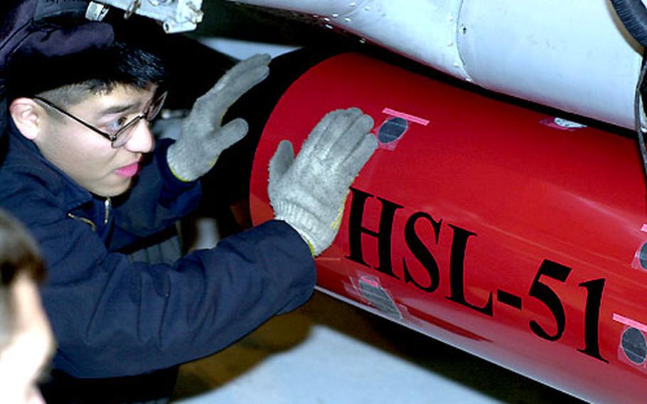Petty Officer 2nd Class Ronnie Cubias checks to make sure a torpedo is properly installed aboard a SH-60B helicopter.
