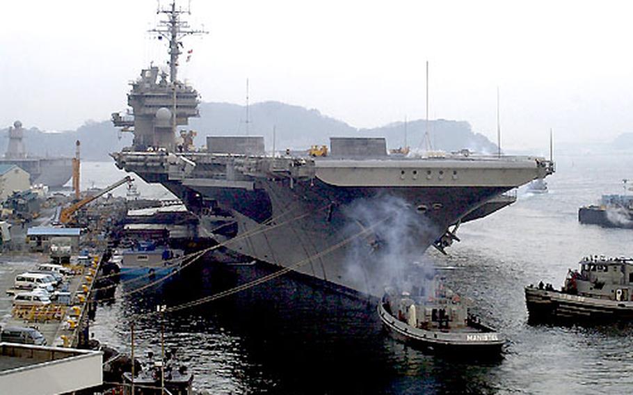 Tug boats prepare to guide the USS Kitty Hawk out of port Monday morning at Yokosuka Naval Base, Japan.