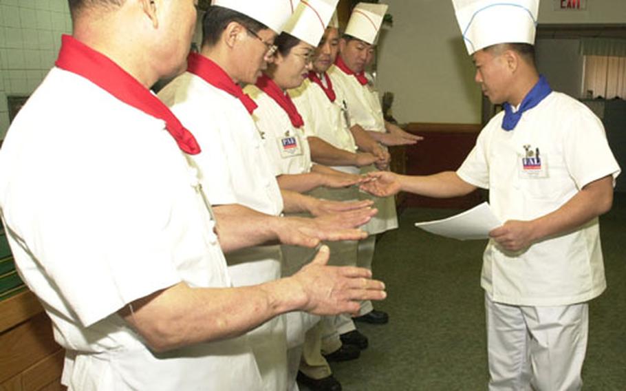 Cooks in the Camp Jackson Dining Facility have their hands inspected for cleanliness by Kim Do Pung prior to the lunch meal on Thursday.
