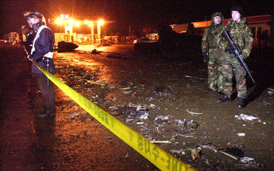 Korean National Police use yellow tape to create a cordon around the crash site of an Osan-based U-2 Dragonlady reconnaissance aircraft while security policeman from the 51st Security Forces Squadron monitor the scene from behind the tape.