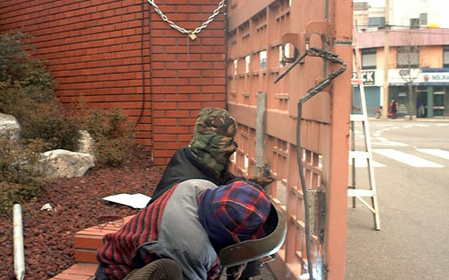 Public works crew strengthening the locking mechanism on the gate at the Army's Camp Henry in Taegu, South Korea.