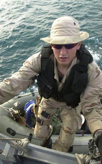 Navy Petty Officer 2nd Class Chris Gentleman climbs a rope ladder from a rigid-hulled inflatable boat to USS Milius after a maritime interception mission in the Persian Gulf.