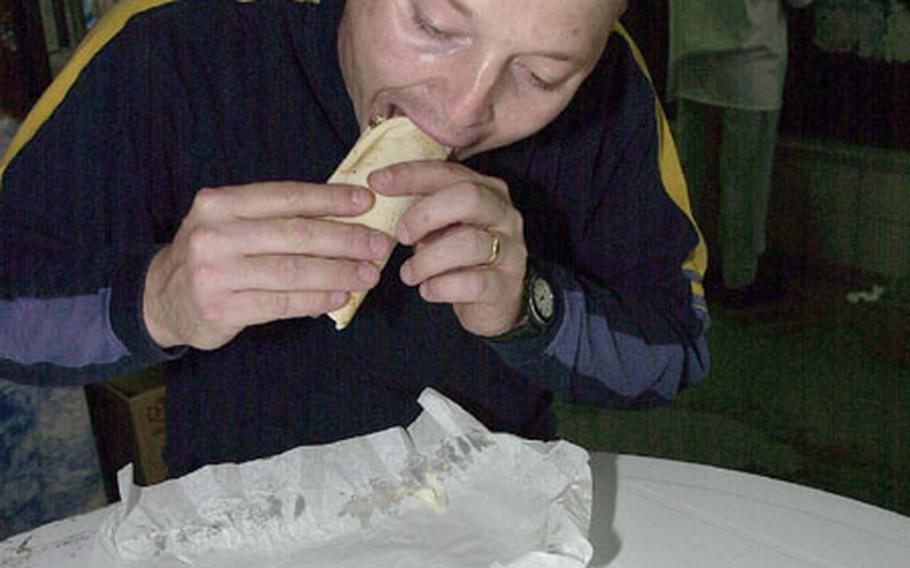 Marine Gunnery Sgt. Shannon Arledge takes a bite out of a shawarma in Manama&#39;s souq. The shawarma is becoming the hottest flavor among troops serving in Bahrain.