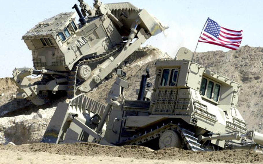 Two D9 bulldozers work in tandem outside at a training range near Camp Virginia, Kuwait.