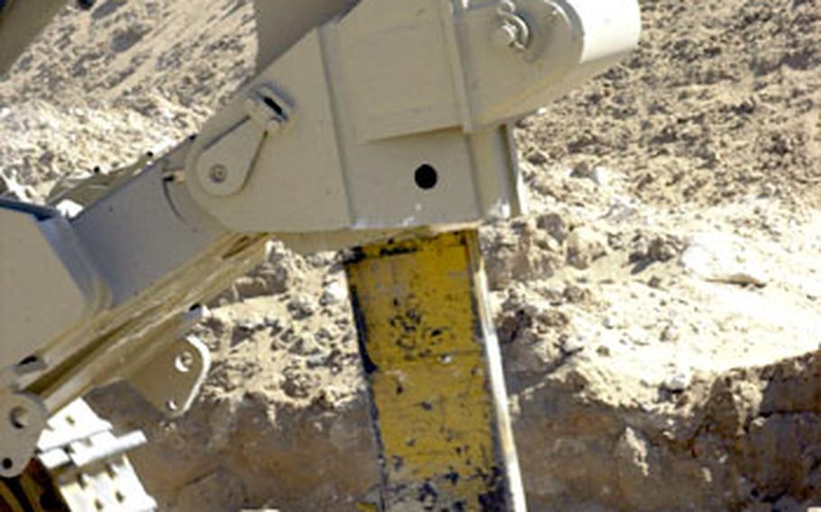 The rear ripper on a D9 dozer digs into the dirt. The clawlike ripper is able to tear through the rock layer, shaking the ground.