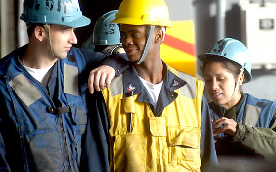 Petty Officer 3rd Class Rodney Mayes, middle, says he&#39;s enjoying his training to become a rig captain during underway replenishments. Here he chats with Petty Officer 3rd Class Neal Ervin and Seaman Jorrel Reich during a break between cargo movements on the USS Kitty Hawk.