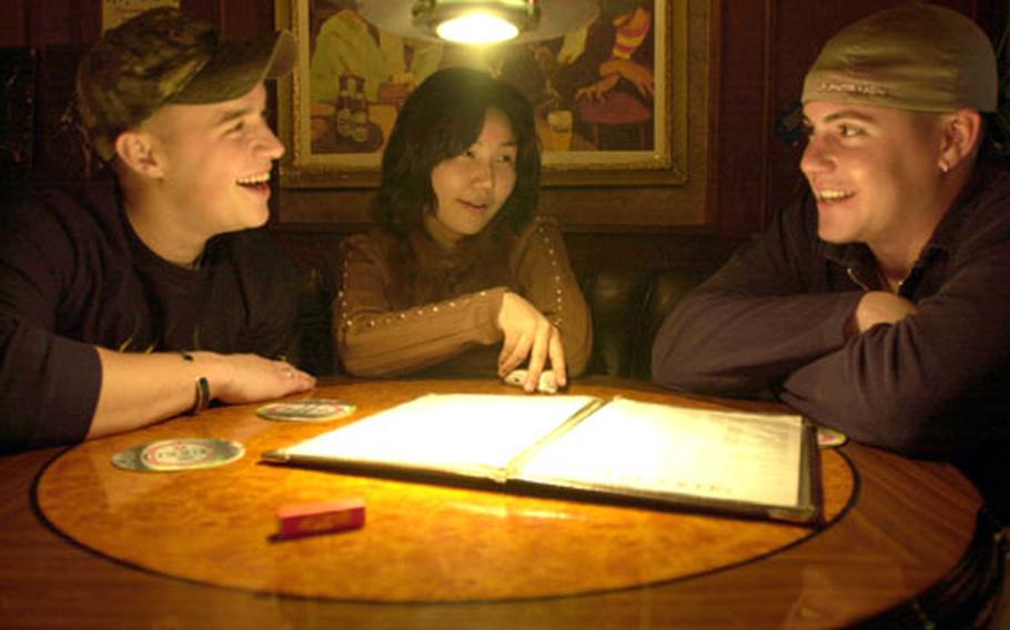 Where does your money go? (From left) Spc. Bryce Mahoney, Serena Lee and Spc. Jonathan Butts discuss dinner choices at a local pub in Itaewon, a section of Seoul, South Korea. The U.S. Army is conducting a survey to determine whether Cost of Living Allowance (COLA) is warranted for the region.