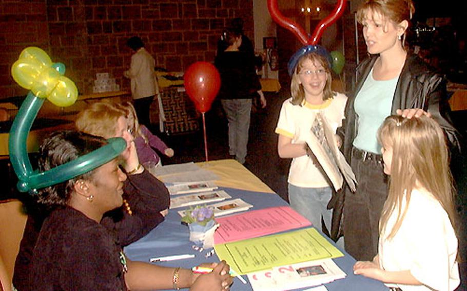 Jeannette Sirois and her three daughters attend a deployment exposition for family members, sponsored by the 221st Base Support Battalion in Wiesbaden, Germany. With her, from right, are daughters Rebecca, 8, Christina, 10, and Samantha, 3, who is hiding behind Sandy McGillivray, one of the women at the table. Sirois is consulting with Undrea Ravenel (wearing a balloon hat) and McGillivray about school plans.