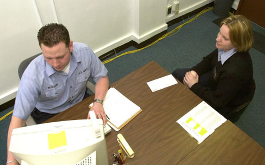 Fireman Apprentice Thomas Redfearn helps Electronics Technician 2nd Class Laura Meu file her taxes at Yokosuka Naval Base Tax Canter.
