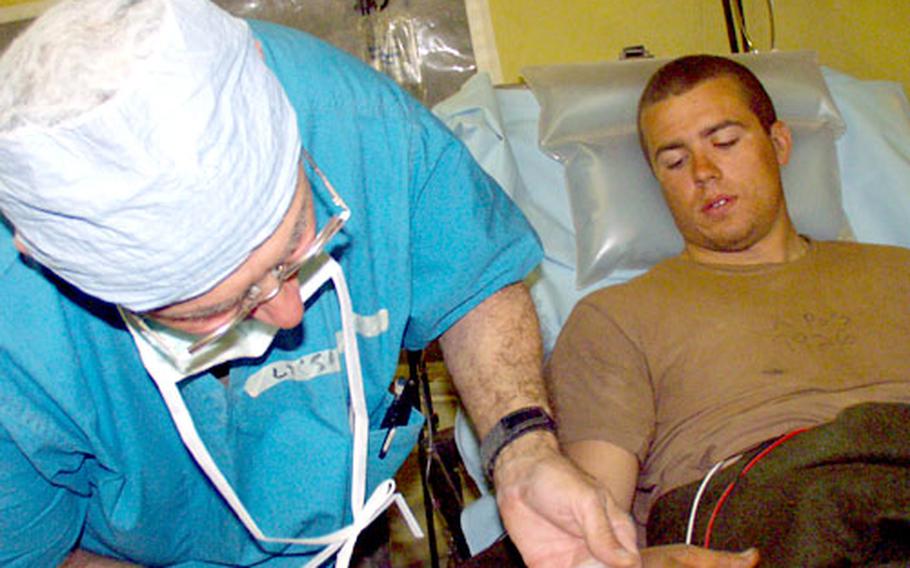 Lt. Col. Gary Saponari, 55, a doctor from the 212th Mobile Army Surgical Hospital, gives medicine to Pfc. Dave Jotich, 19, of the 3rd Infantry Division’s 1st Battalion, 15th Infantry Regiment. Jotich received shrapnel in his leg from an explosion along a highway south of Baghdad.