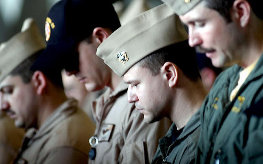 Sailors bow their heads in prayer during a memorial service for Lt. Thomas Mullen Adams Thursday on the USS Kitty Hawk.