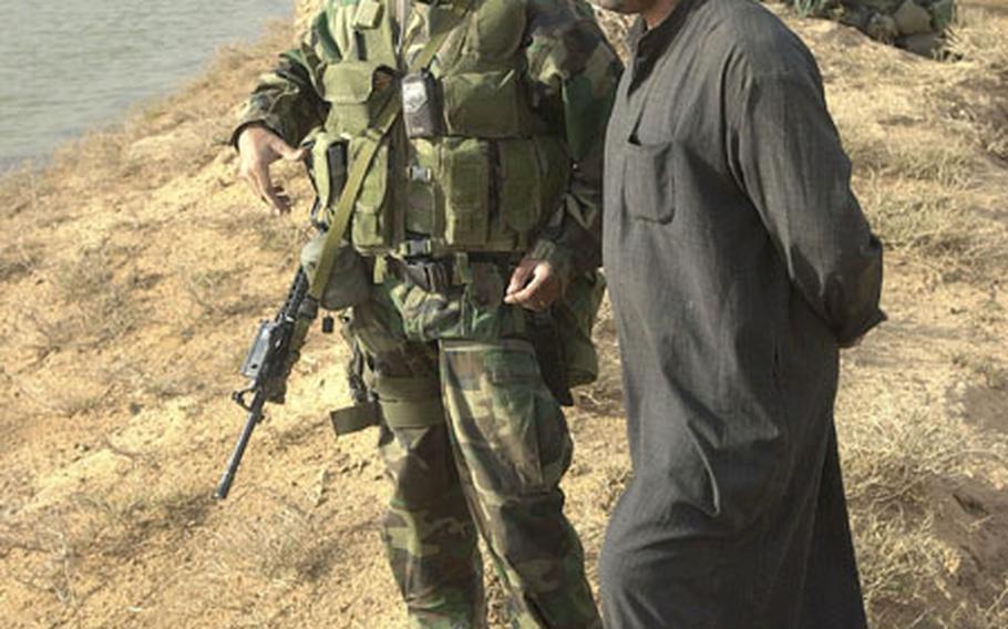 Marine 1st Sgt. Horst Jejjoni speaks with a local Iraqi villager near Al Fahr, Iraq. Jejjoni, an Arabic speaker, used his language skills to ease the fears of Iraqis and Marines alike during the campaign in Iraq.