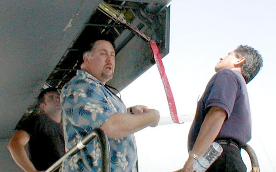 Aerospace engineer Alex Balce, right, and aircraft examiner Jamie Montgomery, center, both civilians with Naval Air Mediterranean Repair Activity, inspect the cracks in one wing of an Air Force KC-135 tanker in Shaikh Isa, Bahrain.