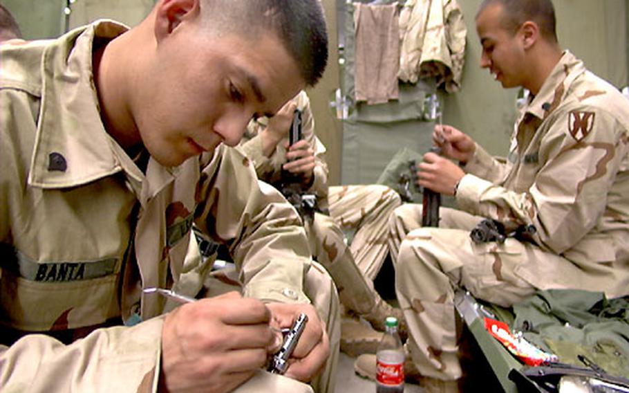 Spc. John Banta, left, uses a dental tool to find hidden dirt on the bolt of M249 squad automatic weapon Monday at Rhine Ordinance Barracks in Kaiserslauten, Germany. His platoon is heading to northern Iraq with a task force from the 1st Infantry Division.