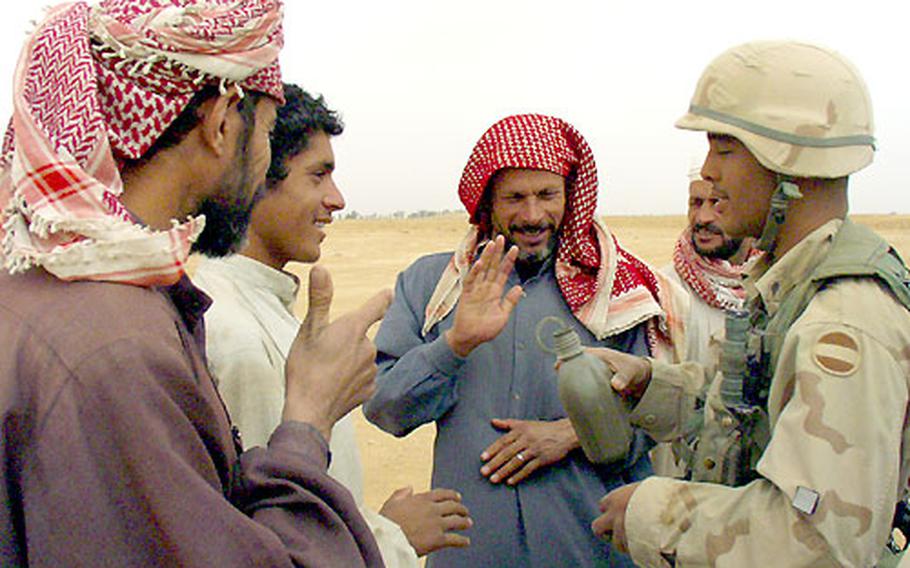 Spc. Brandon Gullen speaks with, from left, Hassan, Sarda, Abbas and She’in. The family has raised wheat, sheep and goats on a farm now used by the U.S. Army since Saddam Hussein's government chased them from their land near An Nasiriyah three years ago.