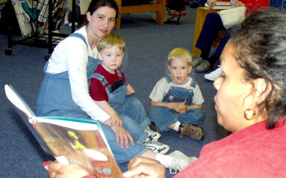 Anne Willson and her two sons, Ammon, 2 (on her lap) and Stephen, 3, listen as DeAnna Braggs, Directorate of Community Activities, reads an Easter tale at the Darmstadt library on Tuesday.