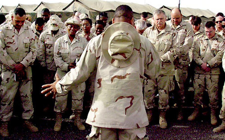 U.S. Army Maj. Cal Stewart, back to camera, leads a prayer Sunday to open an Easter service at Camp Arifjan, Kuwait.