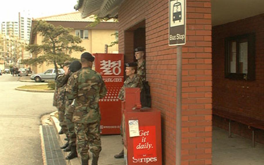 These soldiers await a bus at Army's Camp Henry in Taegu, South Korea. The bus shelter behind them was built with money the 20th Support Group won through taking part in the Army Communities of Excellence award program.