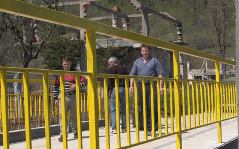 Bosnian returnees to the village of Trakilovici cross the newly opened bridge in their village on Saturday. The Finnish Civilian Military Cooperation team helped rebuild this bridge and another, plus 3.5 kilometers — about two miles — of road to show the pre-war Serb villagers that their return to their former homes will be supported.