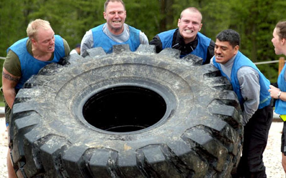 Members of the We'll See You at the Finish Line team, composed of American and Danish Task Force Med Eagle troops, strain to flip a large tire in the last event of the survivor games at Eagle Base in Bosnia and Herzegovina.