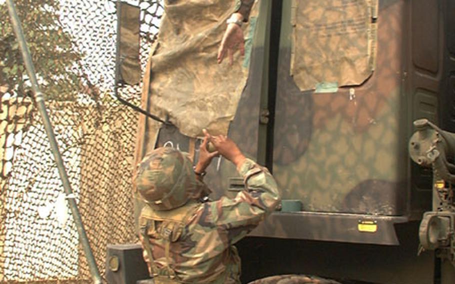 At Army's Camp Walker in Taegu, South Korea, Spc. Lakeshia Thompson (standing) works with Spc. John Schaefer to cover windows of their satellite communications vehicle during unit training exercise. Both are members of 229th Signal Company, 307th Signal Battalion, out of Camp Carroll in Waegwan, South Korea.