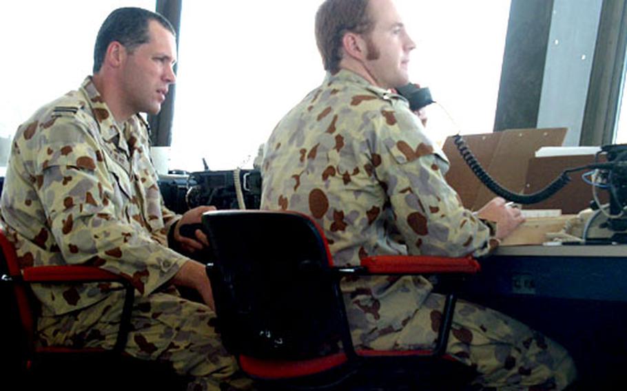 Flight Lt. Michael Duyvene De Wit, left, and Flight Officer Andrew Chapman converse with an aircraft from the air control tower at Baghdad International Airport.