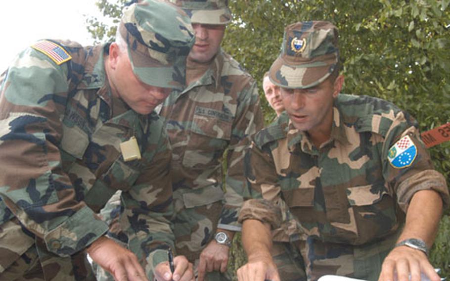 U.S. Army Sgt. Stacey Dawson of Joint Military Affairs, left, takes down the information Friday about a demining team's productivity at a mine field just outside Eagle Base's gate from one of the team's members, Sgt. 1st Class Emir Hadzikadunic, of Demining Battalion of Federation military from the Muslim-Croat part of Bosnia and Herzegovina. Dawson's translator Damir Osmanovic, pictured center. Stabilization Force troops monitor demining by Bosnian armed forces, set their productivity rates, and help when they can with demining equipment.