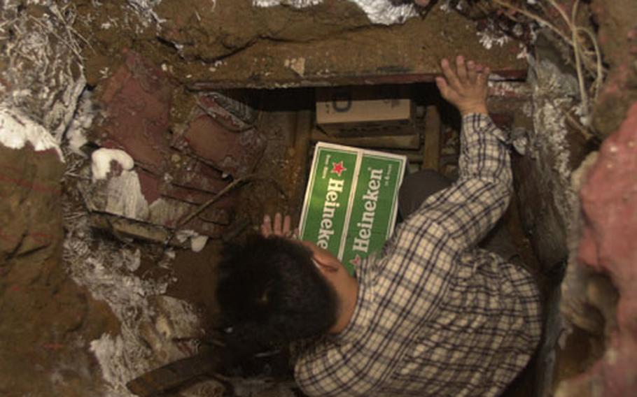 A South Korean customs agent stands in a tunnel that smugglers used to move 62,000 cases of wine and beer from a Hannam Village storage container to a fake storefront off-base.