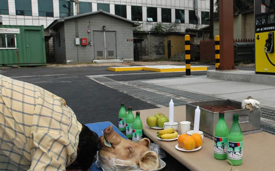 Ken Pickler, chief of the transportation branch for the Far East District Corps of Engineers, bows before a pig's head during a ceremony Thursday for the opening of a two-pump gas station at the FED Compound. It's a Korean tradition to put money in the pig's head as a way to bring good luck.