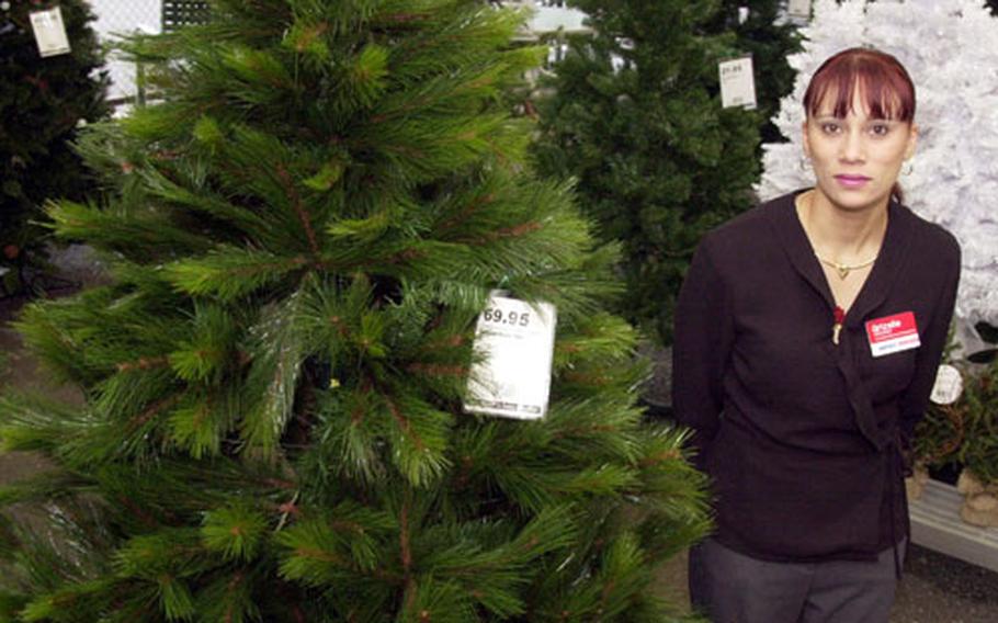 Assistant Manager of the Four Seasons store, Grizelle Fivecoats stands next to the display of Christmas trees at Yokota Air Base. The Four Seasons store is having the grand opening of Toy Land in preparation for the Christmas buying season on Saturday.