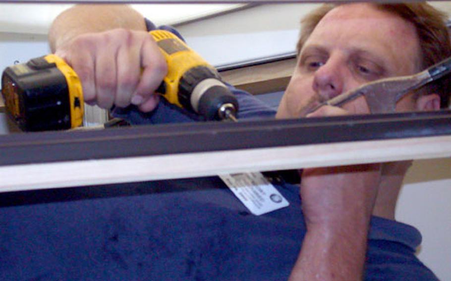 David Roberts affixes one of the 130-pound stained-glass windows to the specially-designed frame in the Pentagon Chapel.