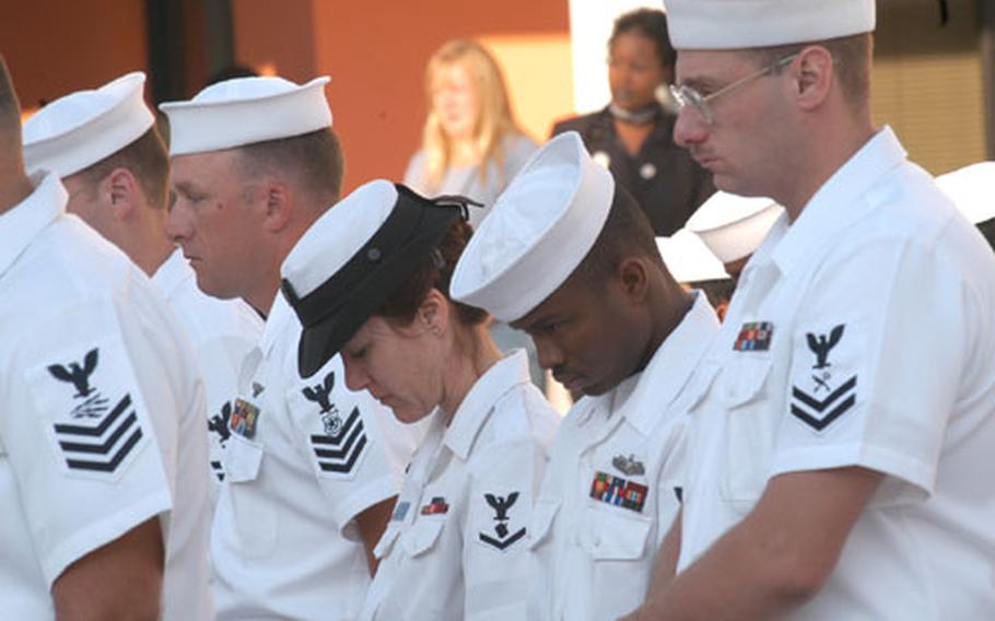 Sailors bow their heads during a moment of silence during a memorial observance Thursday at Capodichino in Naples, Italy.
