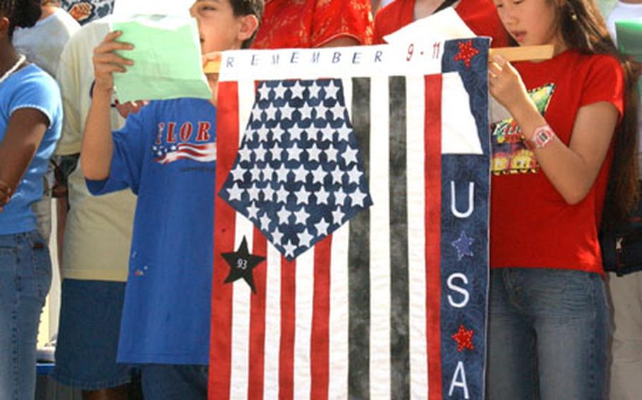 Students from Arnn Elementary school at Camp Zama's Sagamihara Housing Area sing "America the Beautiful" during a 9-11 Remembrance Ceremony Thursday. The flag some of the students are holding was designed by Arnn students, and each element represents a significant event of the day's tragedies, from the collapse of the World Trade Center to the heroic actions of the passengers of Flight 93.