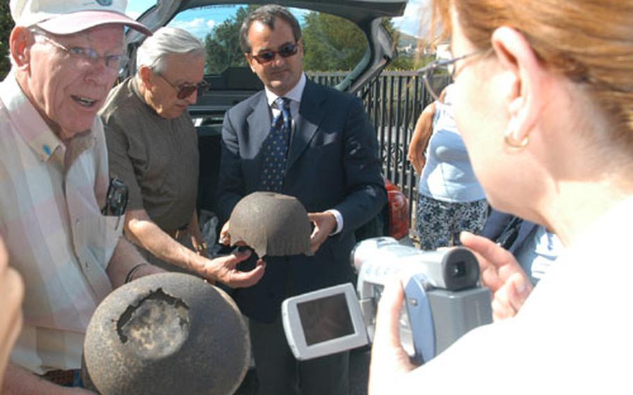 Former 36th Infantry Division soldier J.W. Hawkins, left, holds an American soldier's helmet found near San Pietro Infine by Fabrizio Carloni, center right, who holds a helmet liner. Looking at the liner is another former division member, Joseph Heiser. Carloni has written a book on the 1943 battle of San Pietro Infine, which Hawkins and Heiser took part in. In the foreground with the video camera is Hawkins' daughter, Janet.