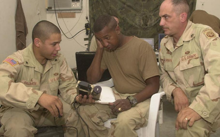 Sergeant 1st Class Charley Little, center, gets a crash course in using a Commander’s Digital Assistant from Spc. Gabriel Palmer, left, and Staff Sgt. Brian Beckman, Company B communications chief. Crash courses in new technology, held in Company B’s busy operations room, are the norm in the field. Officers call techno-geek Beckman and radio expert Palmer the "dream team."