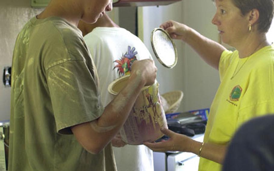 Matt Norwood, left, checks out a small amount of paint he has left after organizing the interior painting of one of the Storks Nest houses on Camp Lester as he talks with his mother, Anne. Matt organized the new paint job for his Eagle Scout project. He is part of Boy Scout Troop 102 on Okinawa.