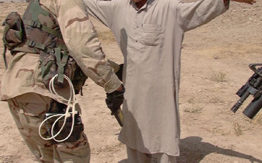 Sgt. Jason Garrison, 10th Military Police Company, checks a young Afghani man at a checkpoint on Friday. In all, the Romanian and American soldiers checked 26 vehicles, each with multiple passengers.