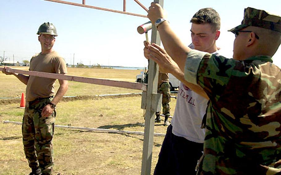 Petty Officer 1st Class Chris Szarek, left, Constructionman Robert Farrell, middle, and Petty Officer 2nd Class Joe Soriano, all Navy Seabees with Naval Station Rota Spain's Public Works Department, help put up the frame of a booth for the Naval Station Rota's 50th Anniversary celebration.