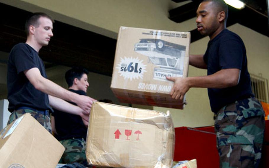 Second Lt. Phillip Root, left, and Airman 1st Class Swan Melton, right, unload a bulk mail truck Tuesday at the Ramstein Air Base Northside post office. Mail volume at the post office doubles during the Christmas season, Root said.