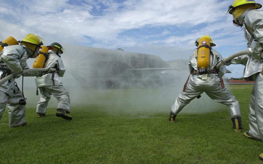 Torii Station firefighters battle the make-believe blaze from the helicopter that crashed at Landing Zone Renegade during the base's annual mass casualty exercise Sept. 26. While there were no flames, red smoke grenades were thrown under the "helicopter" to simulate them.