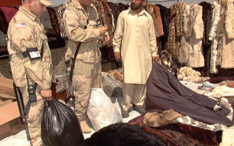Spc. Kevin Lee, center, settles for a price of $47 for a fox blanket Friday, while his buddy, Pfc. James Williams looks on. The starting price for the blanket was $80, Lee said.