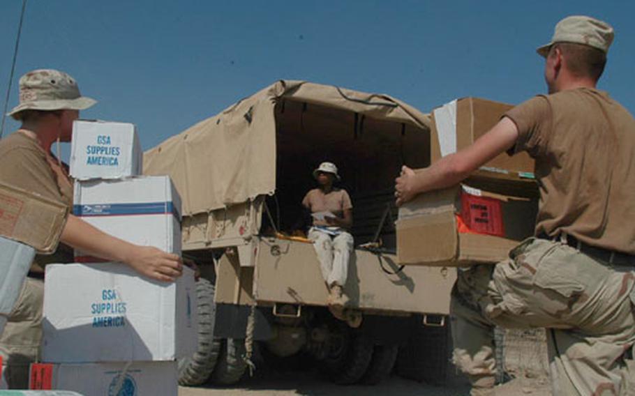 Spec. Suzanne Myers, left, and Sgt. Joseph Turner pick up boxes to carry into the 541st Corps Support Battalion's Tactical Operations Center as Sgt. Crystal Brown sorts letter mail. All three are members of the U.S. Army Reserve's 79th Quartermaster Company at Logistics Base Seitz, located a few hundred yards north of the Baghdad International Airport perimeter. The battalion is made up of reserve, National Guard and regular Army troops.